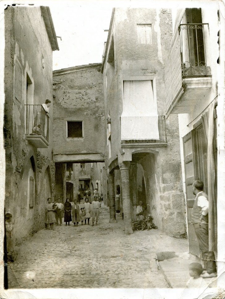 Probablement  una de les fotos més boniques que es conserven del Cabassers de primers  del segle XX. Quins carrers més bonics que tindríem si s'haguessin  conservat les porxades. Les dues columnes que es veuen avui formen la  Font del Mulo, feta el 1943.