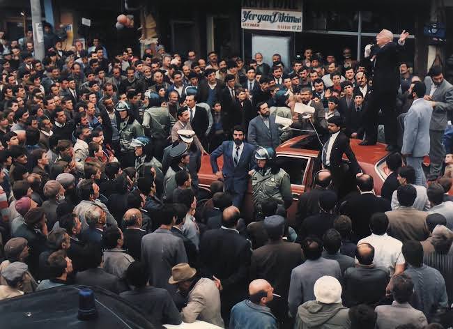 Bu fotoğraf, bir liderin sadece kürsülerde değil, imkânsızlıklar içinde de nasıl inançla mücadele ettiğinin en güzel kanıtıdır. Makam arabasının üstünde bir sesleniş değil, bir diriliş var burada! Erbakan Hocamız, inancın ve azmin ne demek olduğunu öğretti bize. 

Allah rahmet