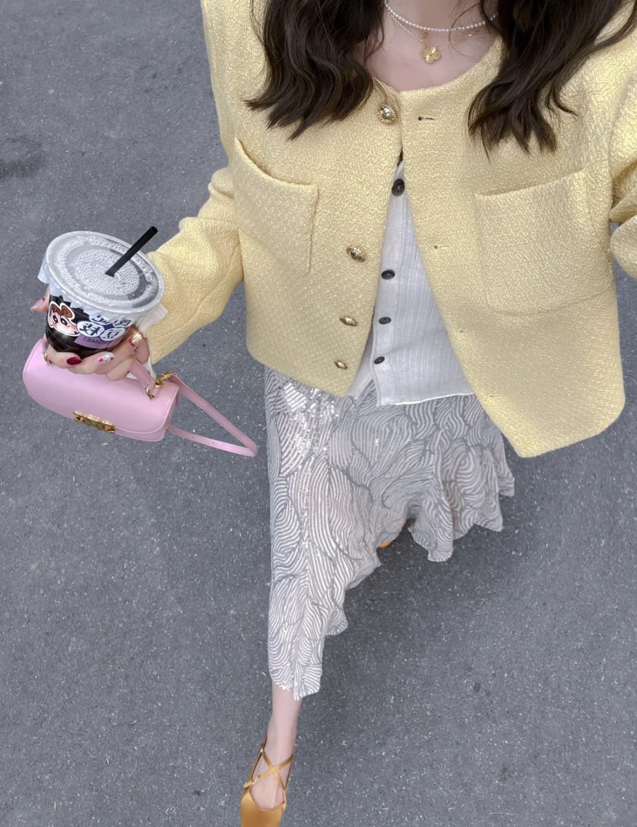 Design_maker21's tweet image. Embracing elegance in a pale yellow tweed jacket over a white top, paired with a flowy patterned skirt and gold strappy heels— accessorized with a pink handbag, a chilled drink, and delicate layered necklaces!