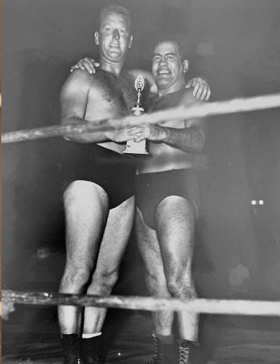 VandalDrummond's tweet image. I'm posting this pic in hopes of identifying the cat standing alongside Ray Duran, and wanna give it another try. A few folks suggested this wrestler might be Red McKim, would any fellow wrestling historians confirm, deny or shrug, "Perhaps?"