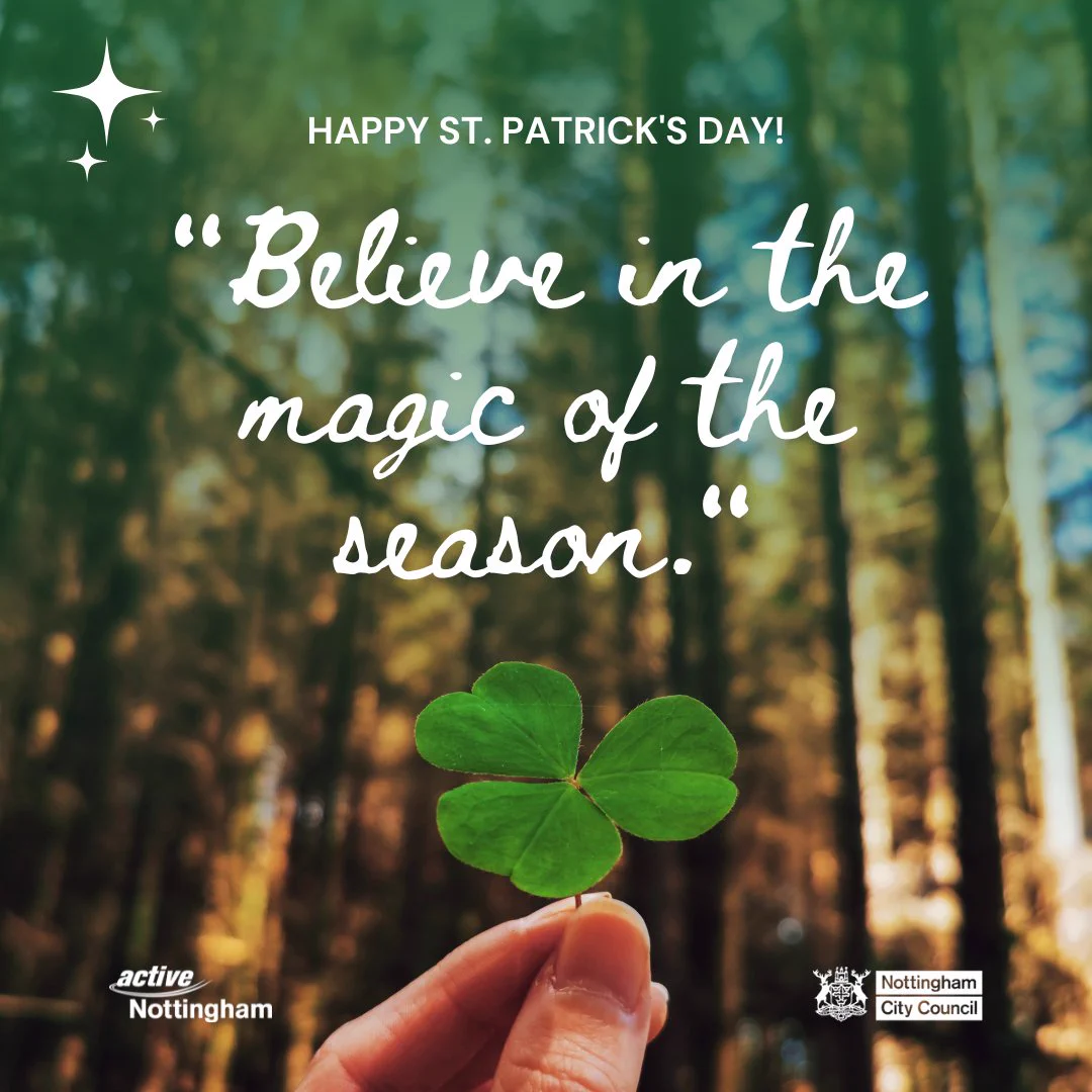 A hand holding a three-leaf clover in front of a blurred forest background. The text at the top reads 'HAPPY ST. PATRICK'S DAY!' Below it, in larger cursive font, is the quote 'Believe in the magic of the season.' At the bottom left corner, there is an Active Nottingham logo. In the bottom right corner, there is a Nottingham City Council logos.