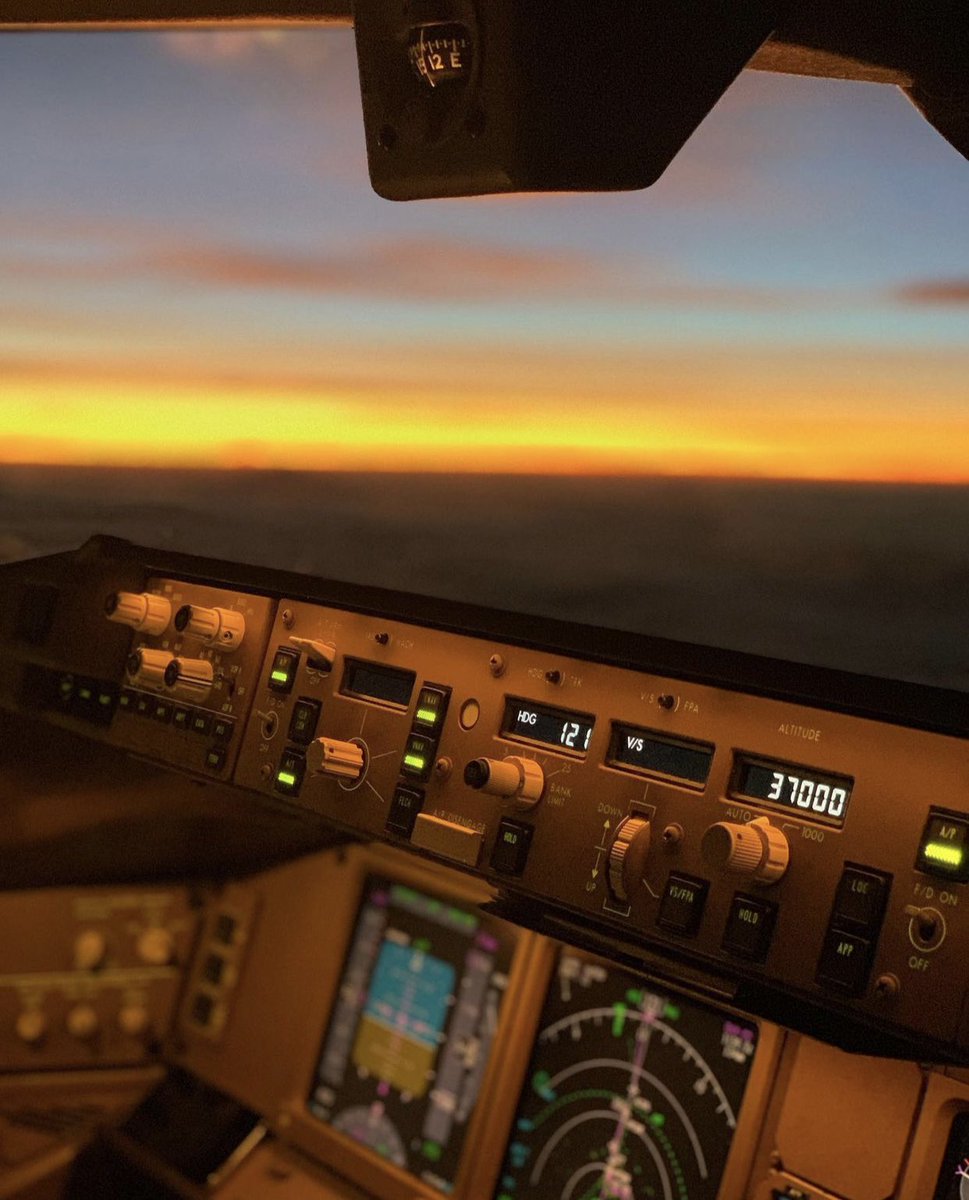 Cruising at 37,000 feet, the Boeing 777’s cockpit is bathed in the golden hues of sunset, creating a stunning contrast between the illuminated displays and the fading horizon. The selected heading of 121°, set on the Mode Control Panel (MCP), guides the aircraft smoothly under