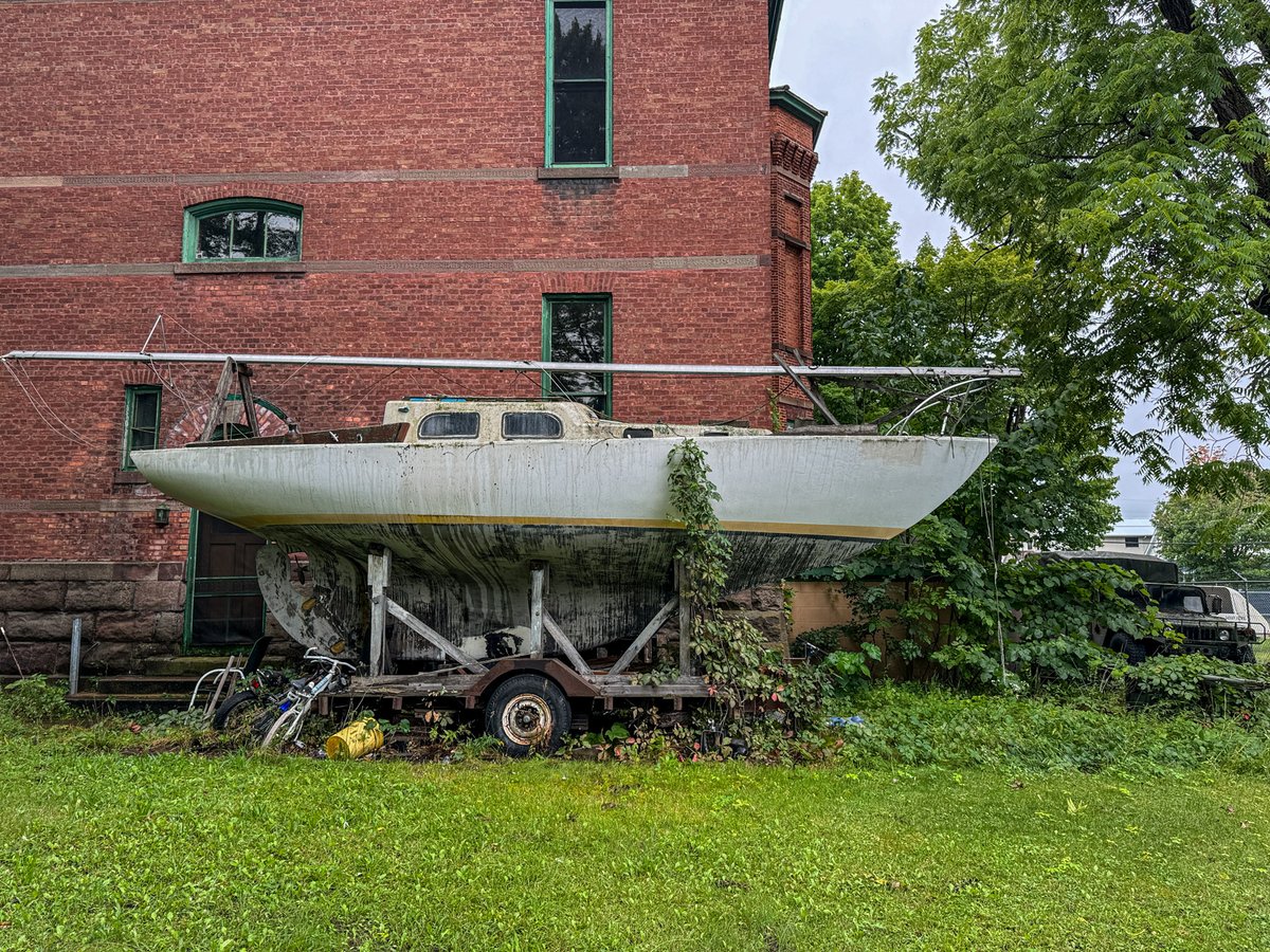 TheHikingCEO's tweet photo. Anchored dreams in a sea of stillness. This weathered sailboat sits far from the waves it was built to conquer, tangled in the grip of time and neglect. A vessel of freedom now grounded, reminding us of adventures postponed and journeys untaken. https://t.co/5BWlhUhh8U