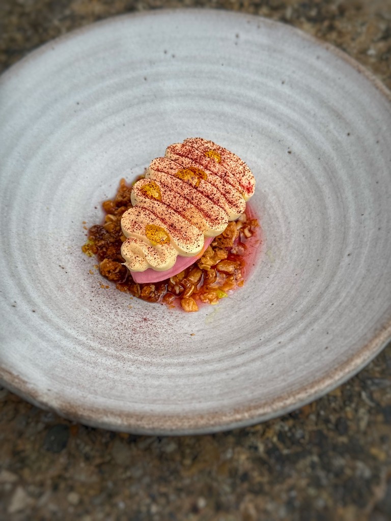 We use rhubarb to make an intense rhubarb sorbet and consommé with cherry blossom. The sorbet sits on oats, caramelised in tagete flower honey and is finished with whipped cream infused with toasted hay, and a rhubarb root oil.