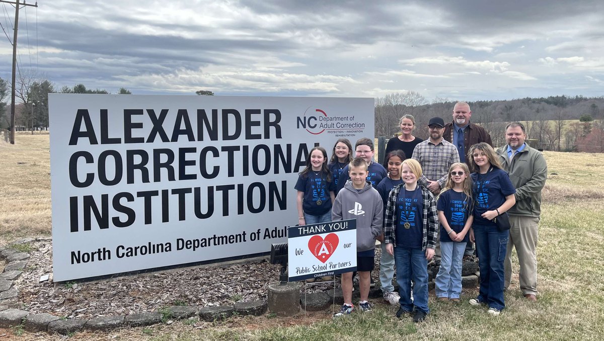 NCCorrection's tweet photo. Hiddenite Elementary School Principal Amy Daigle and some of her students placed a sign at the entrance to #NCDAC's Alexander Correctional this week, to thank the facility's staff and the members of its "Offender Men's Club" for their support of Alexander County schools ! 📚✏️ https://t.co/H7YwWQ8O8Z