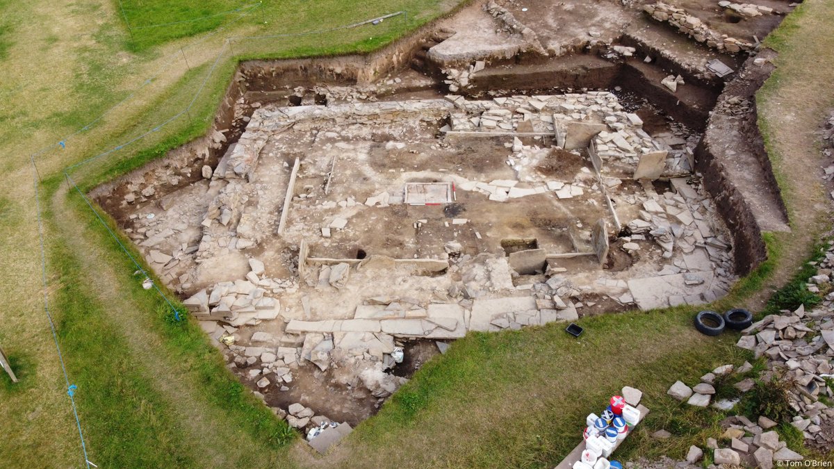 Aerial photo of the excavation of the stone remains of a prehistoric building with low stone walls and hearths appearing