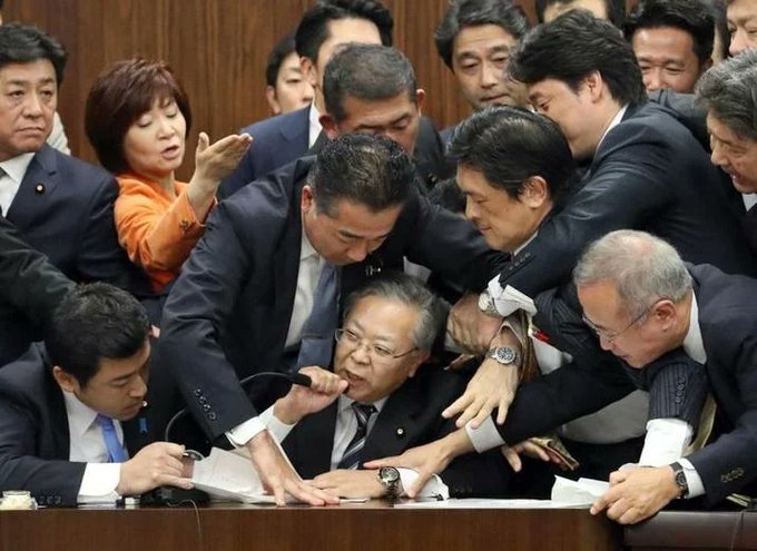 Many people trying to stop one man from speaking into the microphone