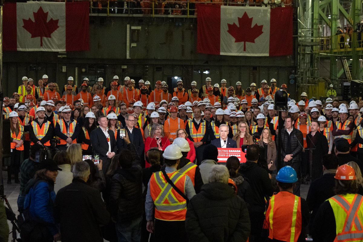 Prime Minister Mark Carney speaks behind a podium during an announcement at Irving Shipbuilding Inc. in Halifax, Nova Scotia. There’s a crowd of workers standing around him.
