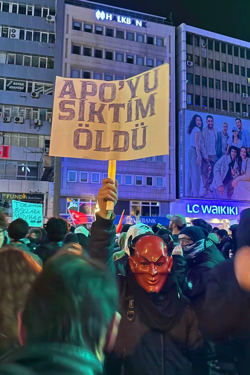 Eylemlerde şeytan maskeli bir gencin pankartı.