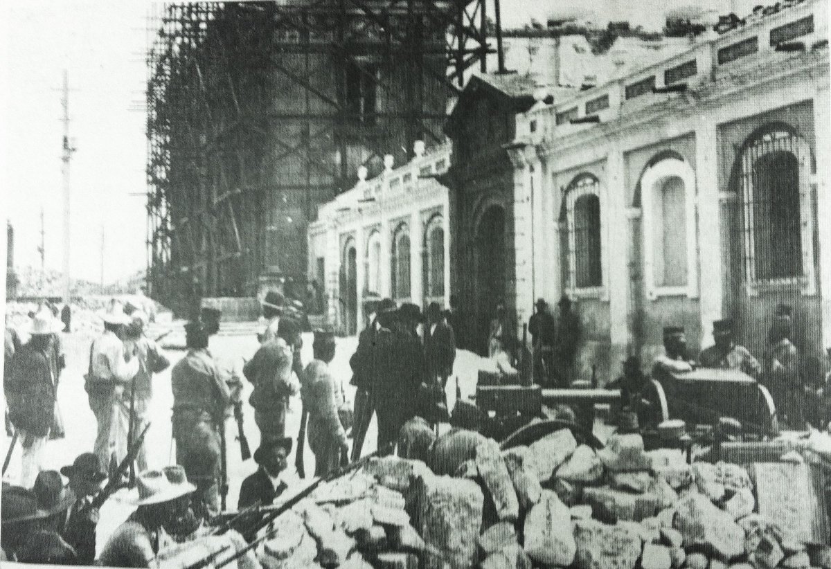 Cd. Guatemala, abril 1920.  Barricada para detener a las tropas de Manuel Estrada Cabrera en la esquina de la 8a. calle y 7a. Av. durante la "Semana Trágica". Atrás se observa la Catedral Metropolitana aun en reconstrucción tras daños de los terremotos de 1917 y 1918.