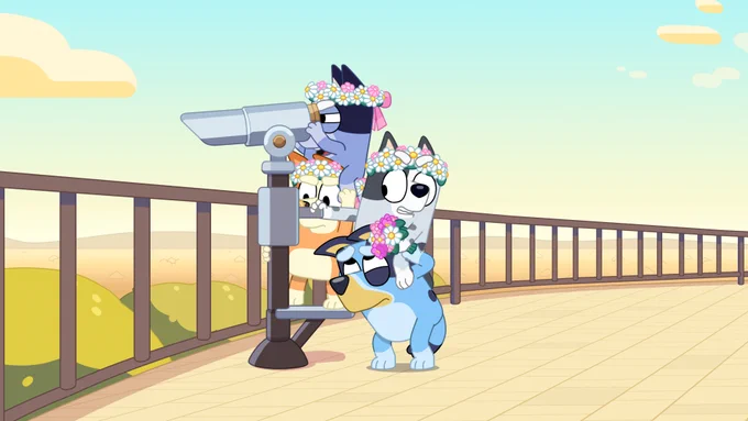 Bluey and her family using a telescope to see into the distance. They have flower bands around their heads.