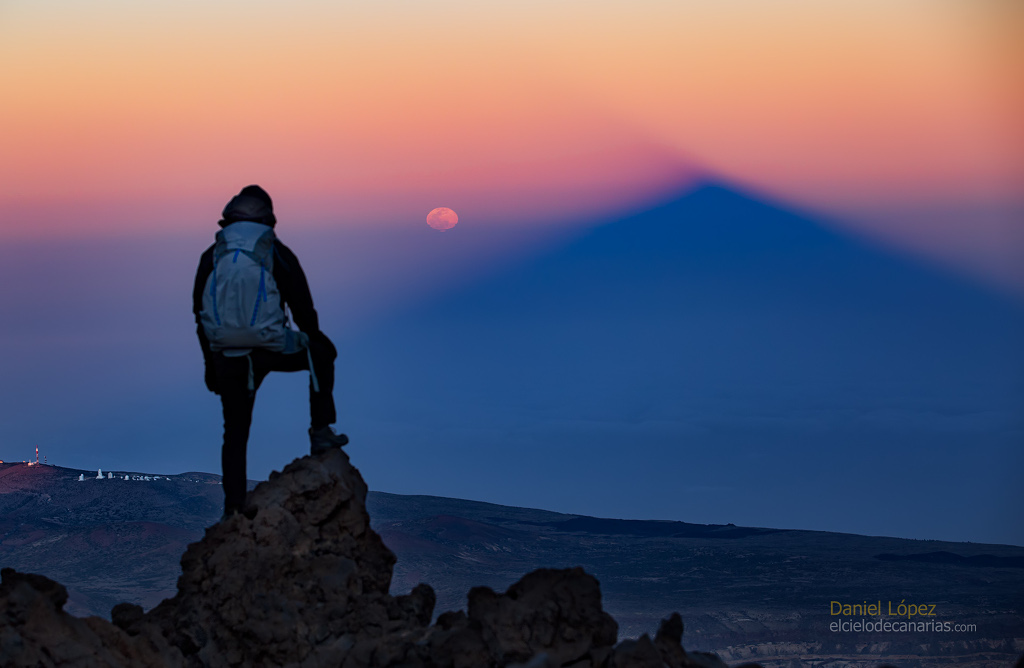 apod's tweet photo. What phase of the Moon is 3.14 radians from the Sun? The Full Moon, of course. Even though the Moon might look full for several days, the Moon is truly at its full phase when it is Pi radians (aka 180 degrees) from the Sun in ecliptic longitude. That's opposite the Sun in planet Earth's sky. Rising as the Sun set on March 9, 2020, only an hour or so after the moment of its full phase, this orange tinted and slightly flattened Moon still looked full. It was photographed opposite the setting Sun from Teide National Park on the Canary Island of Tenerife. Also opposite the setting Sun, seen from near the Teide volcano peak about 3,500 meters above sea level, is the mountain's rising triangular shadow extending into Earth's dense atmosphere. Below the distant ridge line on the left are the white telescope domes of Teide Observatory. Today, March 14 2025, the moon is Pi radians from the Sun at exactly 06:55 UTC. That's about three minutes before the midpoint of the March Full Moon's total lunar eclipse.

Image Credit & Copyright: Daniel Lopez (El Cielo de Canarias)