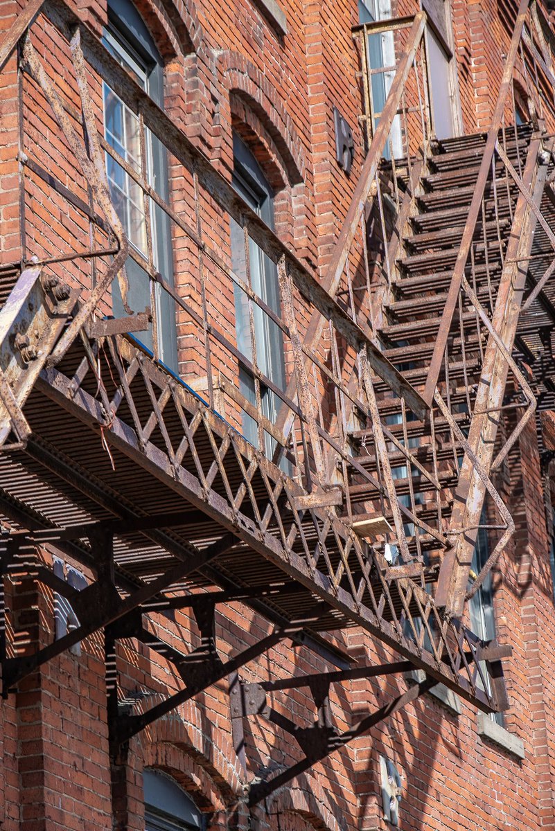 Escape 2025; a rusty, century old fire escape attached to the side of an old industrial building in Cleveland, Ohio.