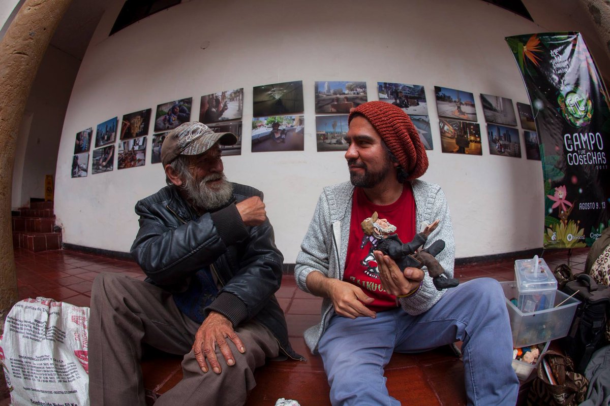 altereddie's tweet photo. Ya que es el día de la felicidad, les comparto una pequeña historia que escribí hace varios años sobre mi amigo Fermín a quien le agradezco sus reflexiones sobre la felicidad. Ya Fermín no es habitante de calle y sigue viviendo en su amada Tunja.

Tunja. Son las 7 de la mañana. Camino por la plaza de Bolívar junto a la famosa esquina de la pulmonía. Hace un frío de esos cargados de viento congelador. Escucho una voz que canta a todo pulmón “la felicidad, ja, ja, ja, ja, de sentir amor, jo, jo, jo , jor, hoy hacen cantar, ja, ja, ja , jar, a mi corazón”, voy en busca del cantante y lo encuentro allí, sentado en una acera. Le dejo unas monedas y me saluda con una sonrisa. Durante todo el día me quedo con el coro de esta canción de Palito Ortega. Me pregunto repetidamente qué es la felicidad para este hombre, pues quede contagiado con las estrofas de la felicidad desde la mañana. Tengo un día de esos de once sobre diez.
Al día siguiente lo busco nuevamente. Le cuento que tuve un día muy feliz gracias a sus coros, me dice “con mis canciones yo le emano energía positiva a la gente, me la gano cantando y no como los políticos que lo hacen robando”.
Fermín López es su nombre, es de Sogamoso y tiene 62 años.
Me dice que lleva en la calle veinte años, que su papá fue uno de los fundadores de acerías Paz de Río y que vivió en Alemania durante cinco años. Cuenta que se accidentó en su trabajo como ingeniero civil y durante un tiempo estuvo en estado de coma, le dio amnesia y se le desconectaron los cables,”dos cablecitos de la cabeza” que lo dejaron con problemas, por esto terminó en la calle y por decisión propia no quiso ser un encarte para su familia.
¿Fermín, usted se considera feliz? Claro, completamente feliz, soy amigo de los que pasan por estos lados, de abogados, concejales. Llego aquí y me voy  a la hora que se me da la gana, no marco tarjetas para nadie, vivo a la salida de la ciudad en un bosque y convivo con la naturaleza, con los animalitos, no le debo nada a nadie. Me da tristeza de esos políticos a los que les toca andar de un lado para otro en carros blindados y que hasta para ir al baño necesitan escoltas. Yo soy libre y canto porque estoy feliz, le animo el día a más de uno.
Lo malo de vivir en la calle es que uno tiene que cuidarse de las operaciones de limpieza social, yo me he salvado de más de una, ¡limpieza social, eso deberían empezarlo por las alcadías, las gobernaciones y el congreso lleno de ladrones! ¿Cuál es el pez favorito de los políticos? el róbalo, je, je.
Ahora Fermín canta “tu tienes una carita deliciosa, despeinada, ja, ja, ja, ja”. Le gustan las canciones de los sesenta y los setenta, Palito Ortega y Leonardo Favio son sus cantantes favoritos.
Fermín es un amante de Tunja, habla maravillas de la ciudad “¡Frío! ¡frío en Alemania, con esos días corticos y nieve por todo lado y sin ver el sol, eso sí es frío, aquí no llega el chikunguña ni ese tipo de bichos, no llegan ni los chulos, bueno algunos pero vestidos de sotana. Tunja no tiene ladrones, excepto los curas y los políticos, es una ciudad muy sana. Aquí el agua es de lo mejor, limpiecita. Los tunjanos tienen fama de asolapados pero yo no creo eso, me gusta la gente de por aquí, es muy buena. Las universidades también son de lo mejorcito”.
Le cuento a Fermín que tengo una exposición en la casa de la cultura y lo invito a que vaya conmigo. Fermín sonríe y me acompaña. Observa las fotografías de habitantes de calle en Los Angeles mientras yo le pregunto si le gustaría posar para que yo lo haga, el me dice entusiasmado que sí, que él es un personaje de la ciudad.
Hacemos una pausa mientras él se toma un café y yo voy por mi kit personal. Traigo mis plastilinas y empiezo a modelarlo. Mucha gente se acerca mientras Fermín, sentado, habla y habla echándole vainazos a todos los que ve por allí con cara de empleados oficiales. Ríe a carcajadas, cuenta anécdotas de su vida, habla de política.
Yo mientras tanto detallo sus zapatos negros gastados y empolvados. Modelo su costal de harina cargado de sus no se ques, su piel enrojecida por el sol y endurecida por el viento, sus manos arrugadas, su chaqueta de cuero, su saco lleno de motas, su vestido de paño barato color café, su reloj inmenso, sus ojos rosados y verdes, sus arrugas pronunciadas en la cara, su barba con infinitos matices de gris, su gorra con un estampado que parece el graffiti de algún pintor callejero confundido.
La gente lo escucha y me observan trabajar. Pasa una hora y cuando Fermín ve su escultura en plastilina sonríe y me felicita, me señala y le dice al público “este es todo un artista”. Nos abrazamos y nos tomamos fotos para la prensa, la televisión y todos los curiosos que ven en este encuentro algo poco común.
Ahora la gente se toma fotos con Fermín, le preguntan todo tipo de cosas, miran al muñeco, lo miran a él. Es el personaje central de la exposición.
