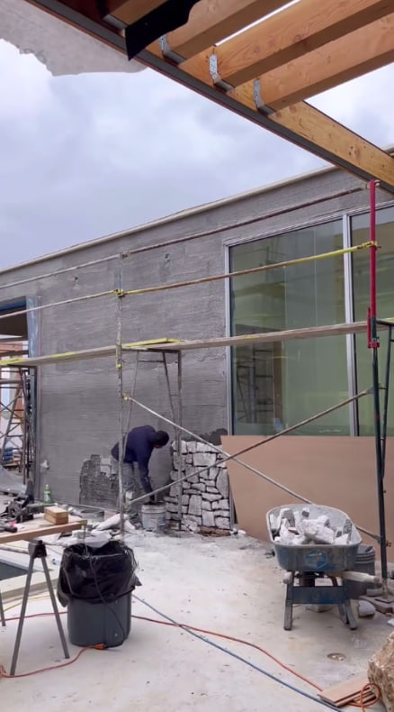 Based on the photo, it showcases a contemporary residential construction design. The stone wall is progressing rapidly, and I’m always grateful for the hard work and dedication of those men on-site. #construction #newgoals2025