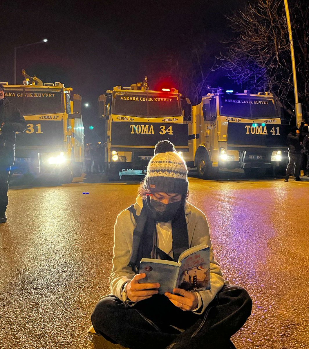 visegrad24's tweet image. Turkish anti-Erdogan student protester reading The Social Contract by Jean-Jacques Rousseau in front of the riot police's water cannons