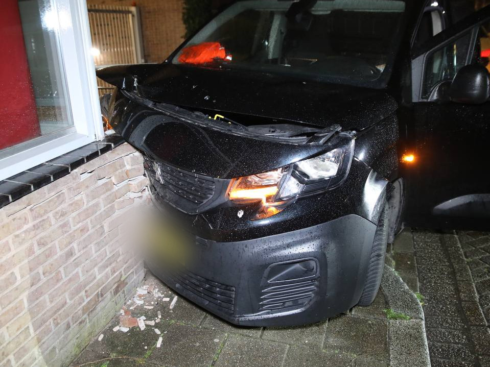 Busje ramt gevel en auto in brand
