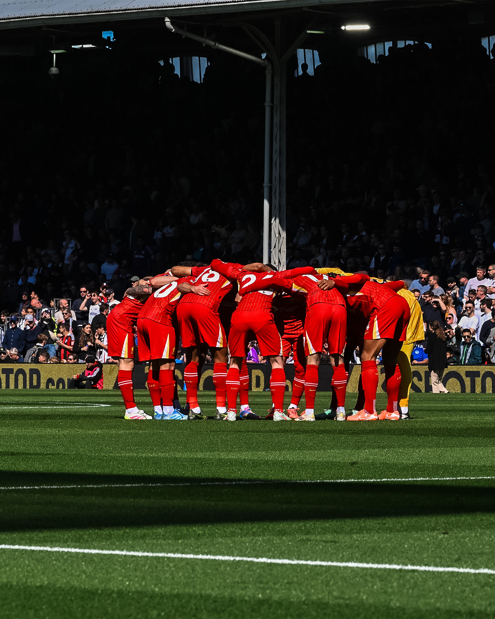 Photography of the Liverpool team in a huddle ahead of kick-off.