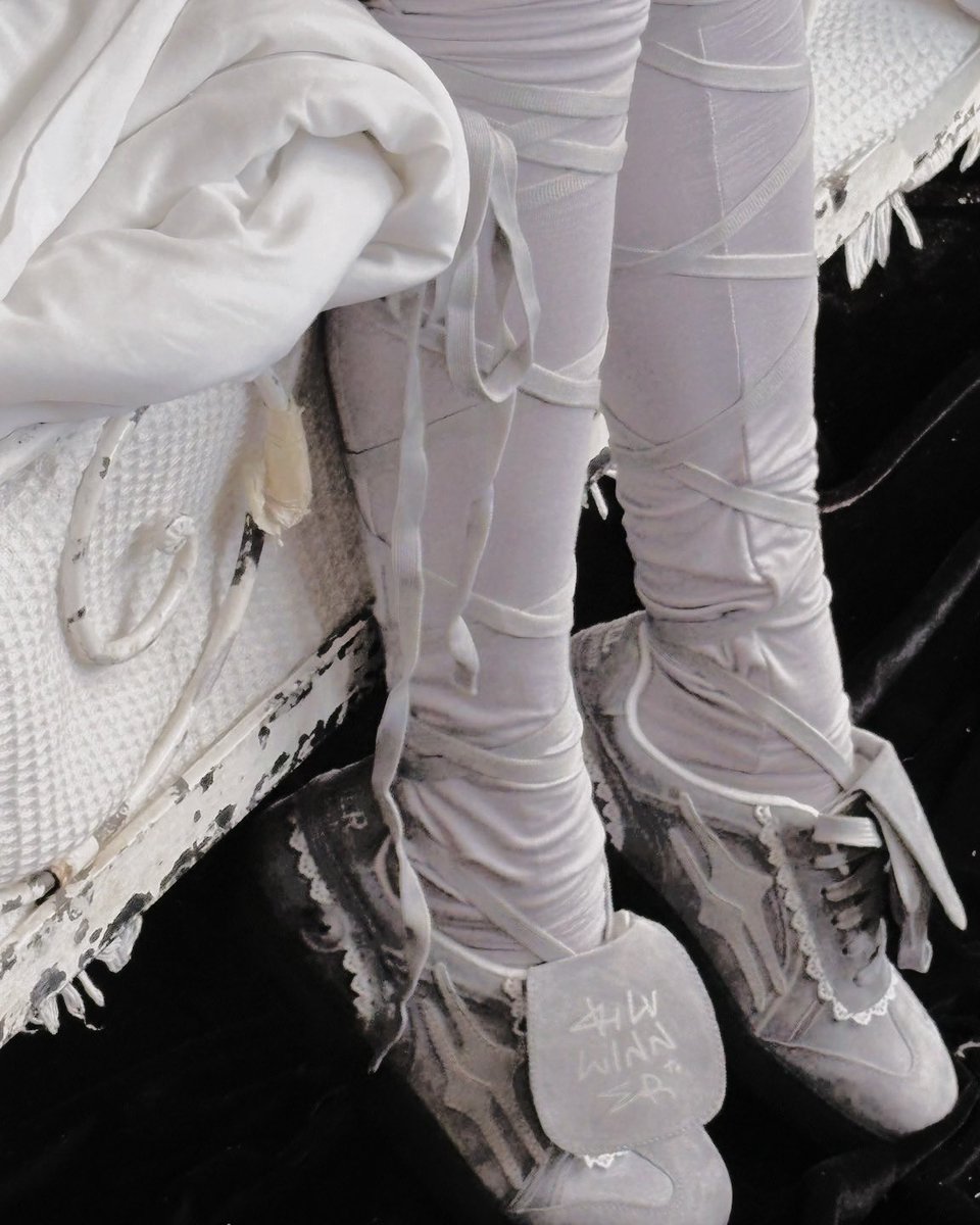 The lace at  her collar blooms like frost-kissed 
petals, a delicate relic of another  time,  where   
dreams  danced  in  worn shoes,  each  tear  a   
testament  to   the  sturdy   feet   that   carried
them     across       the      stage      of      youth