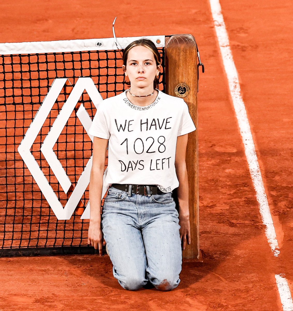 TorresErwerle's tweet photo. En 2022, esta chica se ató a la roja de Roland Garros. 

Fue en forma de protesta y tenía una remera que decía "Nos quedan 1028 días". 

Mañana se cumplen esos 1028 días.

¿Que crees que va a pasar? https://t.co/0g8d7LQ6Gs