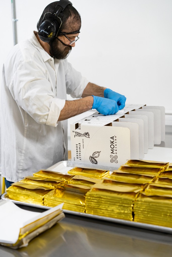 Moka Origins’ chocolate makers pack the bars after they’re wrapped in gold foil.
