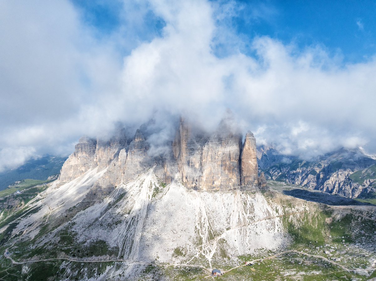 Above the clouds at Tre Cime di Lavaredo, the Dolomites reveal their grandeur. Peaks wrapped in mist, dramatic cliffs, and trails(I saw people walking on top of the mountain) waiting to be explored.  #Dolomites #TreCime #AerialView #MountainMagic #AdventureAwait #italy