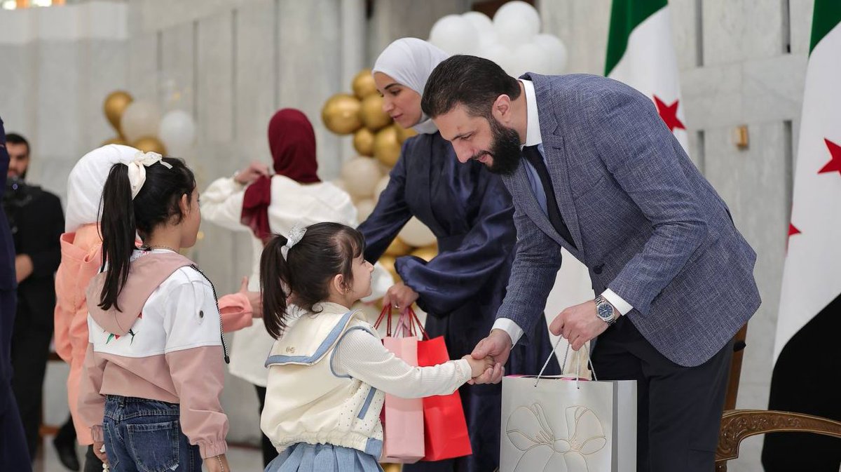 Charles_Lister's tweet photo. #Syria's interim President Ahmed al-Sharaa &amp; his wife, Latifa al-Droubi gathered children of those killed in conflict, giving them gifts for #EidAlFitr &amp; setting up a playground in the grounds of the Presidential Palace. https://t.co/2fBQTAbHxP