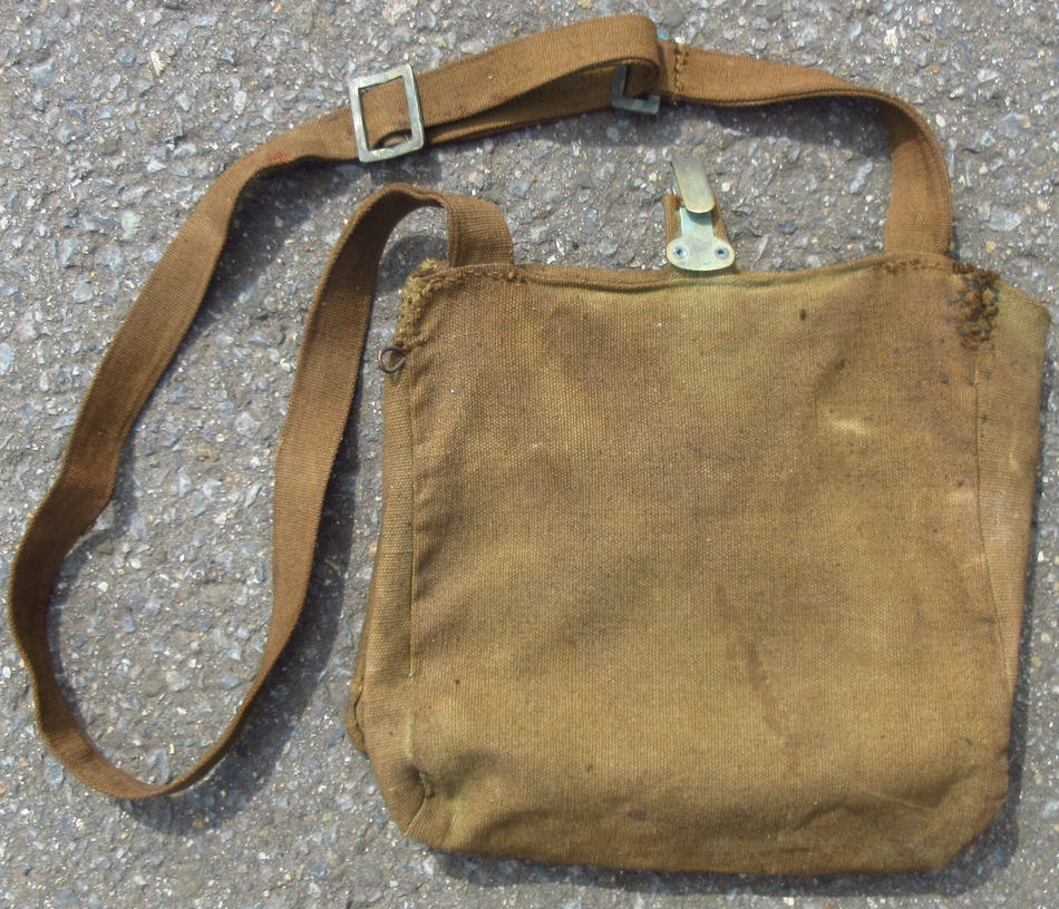 日本陸軍あるいはそれを模した民間用雑嚢かと思いますが果たして・・
材質はキャンバス生地製にて大正期頃までの雑嚢のように内部の留め紐は皮革製で左右にオスメスのある調整金具の付いた形状ですが、蓋部分の皮革紐の縫付部は表面にも皮革が使われています。
袋本体上部中央に帯革留めがあります。