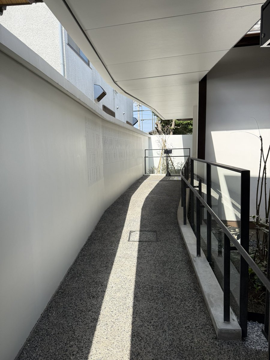 remgoto's tweet photo. 前から行きたいと思っていた、SALHAUSさん設計の「三鷹市吉村昭書斎」に行ってきた。@Arch_Hino 

京王井の頭線、井の頭公園駅より徒歩数分の場所にある。

この地に住んだ作家の吉村昭が書斎にしていた建物を移築して公開している施設。書斎の横に展示スペースのある小さな建築が併設されている。

非常に小さな建築ではあるけれど、建築でしかできないこと、建築にしか出来ないことが具現化されている実感があり、めちゃ良かった！そして、隅々まで考え尽くされている設計にめちゃくちゃ頭が下がる思い、、、。素晴らしい、、、。

道路からは、正面に書斎が見えるように配置して、その横に控えめに受付、展示スペース、トイレなどが入る交流棟が配置されている。

交流棟からは、庭越しに移築された書斎が、色々な方向からぐるりとみわませるようになっていて、またガラス越しに見ると書斎が展示物のようにも見える感覚があり面白い。（庭の植栽は、吉村の旧邸の庭に植えられていたものと同じものが選ばれているとのこと）

交流棟の平面型は、L型で書斎より目立つことを意図的に避けるような形状になっている。そして、書斎の内部に入るためのアプローチ空間にもなっている。

そのような控えめな平面型でありながらも、天井の高さや切妻の天井の形によって、個性は確実に付与されている。その存在感の作り方とバランス感が絶妙で、上手い設計だなぁと感心させられてしまう、、、、！

交流館から一回外に出て、書斎に向かうのだけど、扉の向こう側は天井高の抑えられたクールな空間で、書斎に入るまでの気持ちも整えられる。作家の経歴を紹介する年表もあり、動線空間でありつつも展示空間の一部にしている。上手い。

そして、違う角度からまた庭が見られるのもとても良い。
同じものが色々な角度や違った形で見れるようにするということは体験を重層化させて、豊かにする効果があるんだと思った。

メインの移築された書斎の内観も興味深く。様々な地域の歴史に関する資料がずらっと並んでいる。僕は吉村氏の作品には詳しくないのだけれど、膨大な資料でのリサーチをベースに小説を書いていたことが伝わり、ジャンルは違うけどもプロフェッショナルの在り方が実感できた。

エントランスの広場は、障がいを持った型向けの駐車場も兼ねているのだけれど、一体型の広場にも使えるような作りとしていたり、脇のベンチもコンクリートに木製ベンチを埋め込むようなデザインにしていたりと、本当に細やかに設計がされていて、体験的な気持ちよさと、建築的発見の知的な快感が同時にくるような感じ。

社会的に開かれていると同時に建築的にも突き詰めようとしているというか。

吉祥寺方面に来られる方には、ぜひ寄ってもらい建築だと思った、、、！内覧会には伺えなかったので、やっと宿題を終えた気分、、、、！

皆様ぜひ！