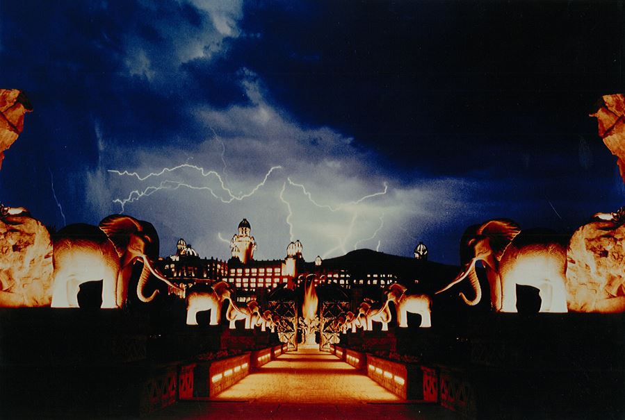 casarchi's tweet photo. I’ve always admired this iconic image of Sol Kerzner’s Lost City in South Africa. It was taken from the Lost City Entertainment Center, designed by Conversano Associates and Steelman Partners, with a view across the “Bridge of Time” — a bridge that genuinely felt like it was shaking, as if an earthquake was underway, as it spanned the distance to WATG’s Lost City Hotel. The photo captures a dramatic night in the South African hinterlands, a scene that, in many ways, reflects the turbulence we face today. However, like all things, life will return to a new normal and be better than ever. Rest in peace, Henry Conversano, Gerry Allison, and Sol Kerzner. #steelmanpartners #lostcity #lasvegas #lasvegasbusiness #lasvegaslife #casino #hotelresorts #gaming #southafrica