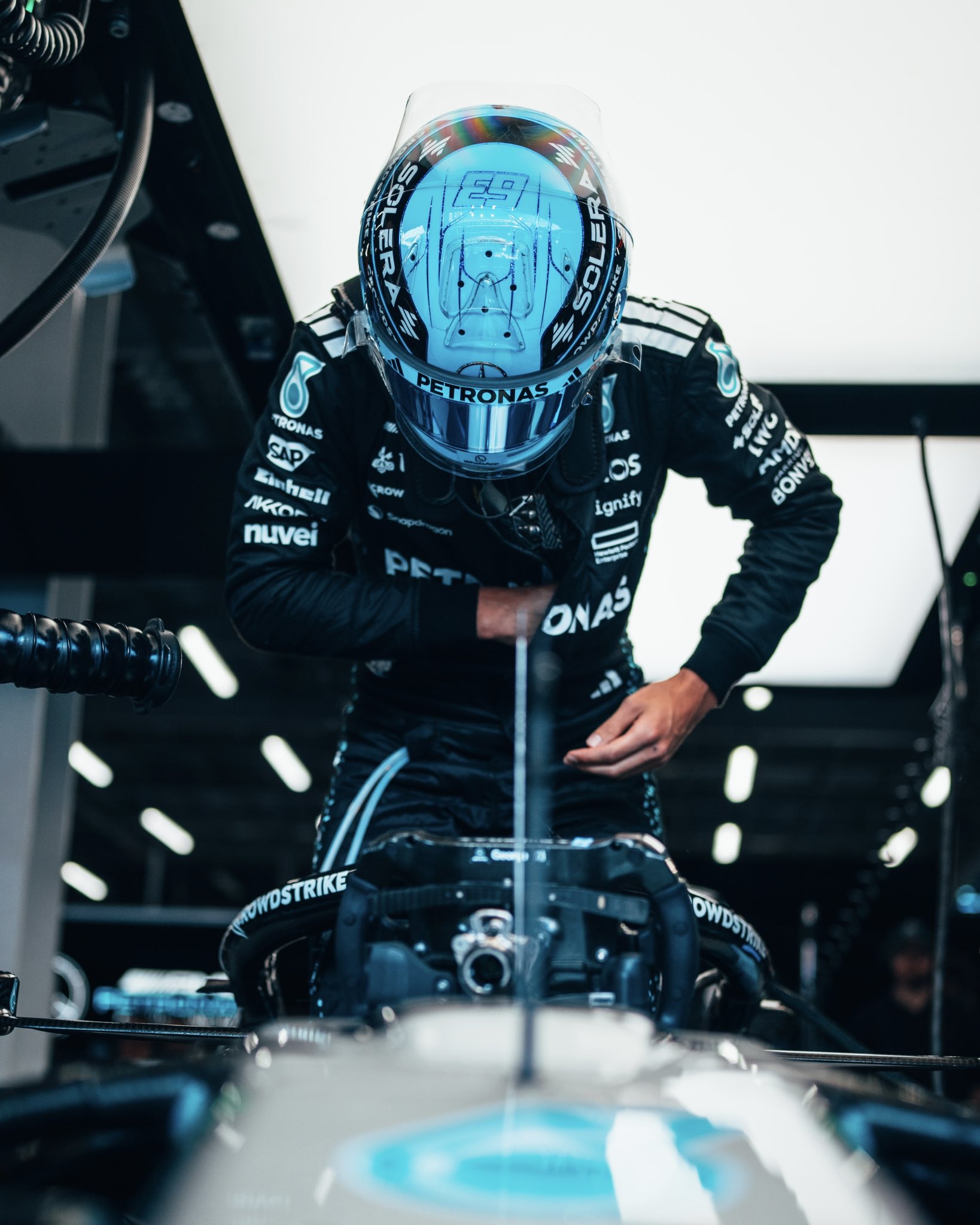 George Russell wearing his race helmet and hopping into the W16