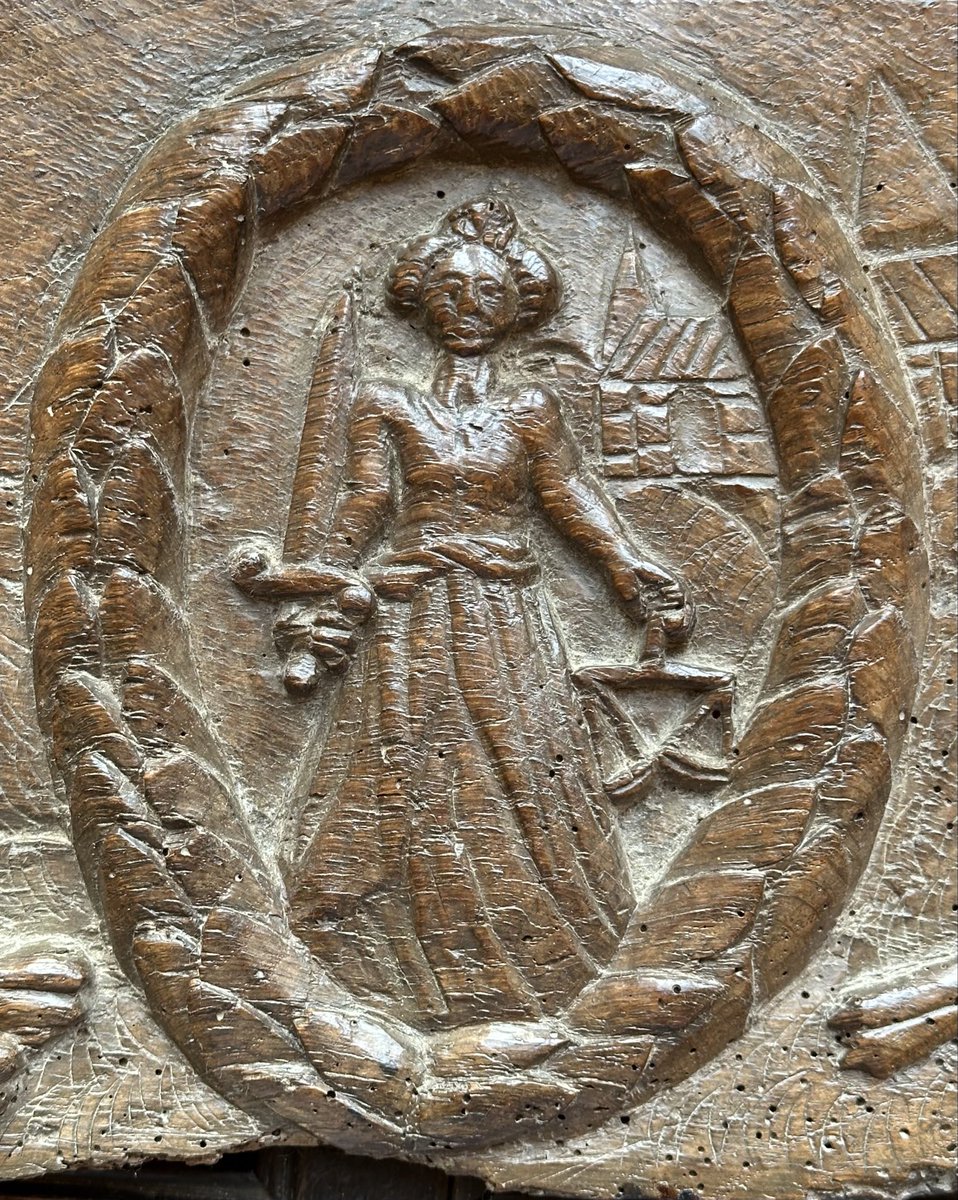 Can you figure out what the lady is wearing in her left hand? There is a sword in her right hand but the object in her left puzzles me.