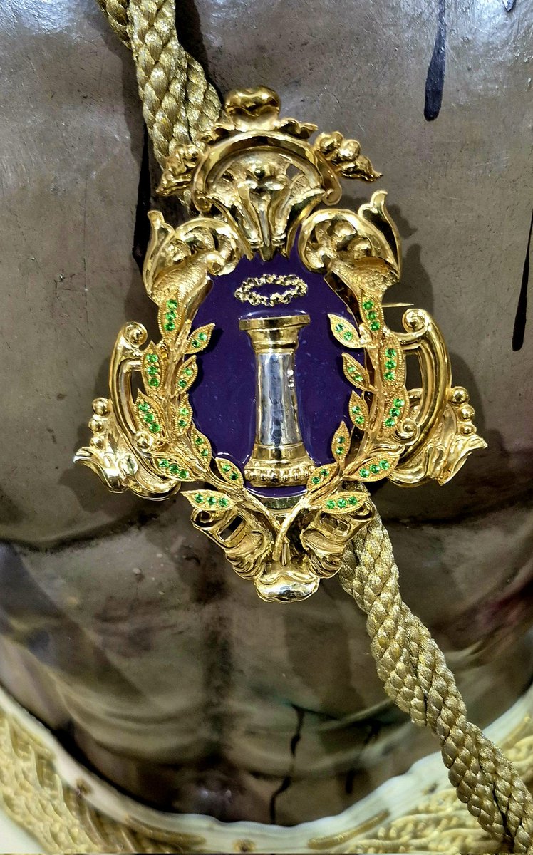 El broche recupera el antiguo escudo de la <a href="/HdaddelaColumna/">Hermandad de la Columna</a> de comienzos del siglo pasado, cuando la hermandad aun no poseía la bella imagen de nuestra titular, María Stma. de la O,  representada en el actual por dos anclas cruzados.
#CofradíasMLG