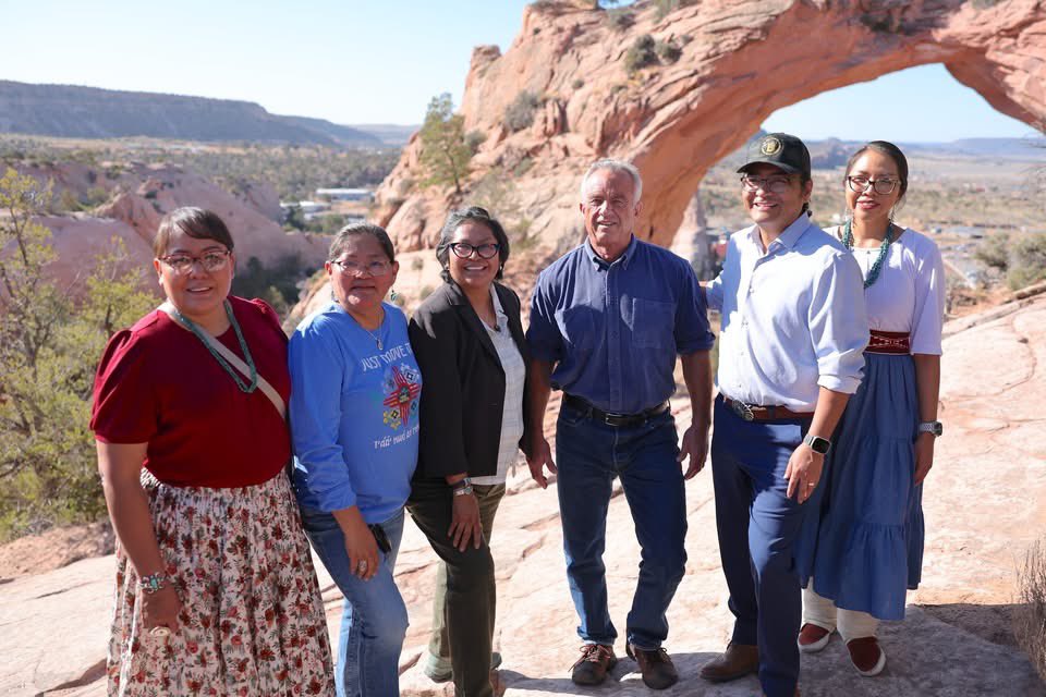 BuuVanNygren's tweet photo. SECRETARY OF HEALTH ROBERT F. KENNEDY JR. VISITS NAVAJO NATION

WINDOW ROCK, Ariz. — Against the backdrop of the iconic Window Rock arch, Navajo Nation President Buu Nygren sat on a sandstone cliff with U.S. Secretary of Health and Human Services Robert F. Kennedy Jr. and Council Delegate Germaine Simonson to discuss critical healthcare access issues facing the Navajo people—and the solutions rooted in sovereignty, tradition, and self-reliance.

Secretary Kennedy, on a national tour, made a significant stop on the Navajo Nation to meet with tribal leaders including President Nygren, First Lady Jasmine Blackwater-Nygren, Speaker Crystalyne Curley, members of the 25th Navajo Nation Council, and officials from the Navajo Department of Health. The purpose of the visit was to better understand how Navajo programs are maximizing federal resources to serve thousands of Navajo people across the Nation.

"I know that you're no stranger to Navajo," President Nygren told Secretary Kennedy. "With your support and help, we will build the Gallup Indian Medical Center because it is in such, such need. It will expand to where we do not have to go to Albuquerque or Phoenix and our people will have a world-class facility."

The visit was deeply personal for Secretary Kennedy, who last set foot on the Navajo Nation 60 years ago alongside his father. His return began with a sunrise hike with tribal leaders from the base of the tribal capital to Window Rock. They were met with sacred prayer, traditional songs by a medicine healer, and ceremonial dances performed by the Dinétah Dancers at the Navajo Veterans Memorial Park.

President Nygren provided additional context about the urgent health disparities on the Nation and the strain caused by the Indian Health Service’s 30 percent vacancy rate.

“As President, I want to emphasize the importance of protecting and maintaining tribal sovereignty among food and healthcare for the Navajo Nation,” President Nygren said.

Secretary Kennedy expressed strong support, making a clear commitment to address staffing shortages and cuts in the Indian Health Service.

“By lifting the IHS hiring freeze and rescinding the hundreds of employee terminations,” Secretary Kennedy said, “it will not happen.”

Secretary Kennedy emphasized that the federal government must go further to empower Native communities.

"Today we learned many things that HHS could be doing to improve the condition of Navajo health...,” he said, adding that securing water will allow the Navajo people to build homes and become self-sustaining again.

A focal point of Secretary Kennedy’s visit was the Navajo Nation’s pioneering of the junk food tax, formally known as the Healthy Diné Nation Act. Passed in 2014 through grassroots mobilization by the Diné Community Advocacy Alliance, the law promotes healthy lifestyles and combats rising rates of diabetes and obesity.

The Indian Health Service reports that one in five Navajo Nation residents lives with diabetes, and approximately 75,000 individuals are prediabetic.

Revenues from the junk food tax have been redirected to support community wellness projects through the Navajo Division of Community Development, according to the Office of the Navajo Tax Commission.

President Nygren also emphasized the need for formal tribal consultations to ensure that the trust and treaty responsibilities are upheld, especially as recent changes at the federal level have impacted social services.

“We strive to live for 102 years as Navajo people, and also with your help and assistance, we look forward to reestablishing and protecting some of the services that your department provides,” President Nygren told Secretary Kennedy.

President Nygren added, “Secretary Kennedy’s visit today shows that our voices are being heard at the highest levels. We’re not asking for charity, we’re reaffirming equity, and we’re building solutions grounded in sovereignty…the Navajo Nation is ready to lead.”