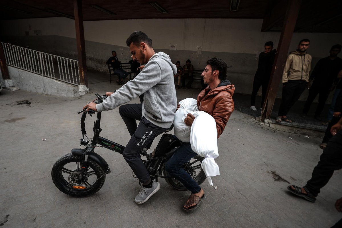 Palestinian men in an electrical bicycle transport the shrouded body of a child ahead of the funeral of victims of an Israeli strike on Shujaiyya neighbourhood, at the Ahli Arab Hospital, also known as the Maamadani (Baptist) Hospital, in Gaza City on April 9, 2025.  (Photo by
