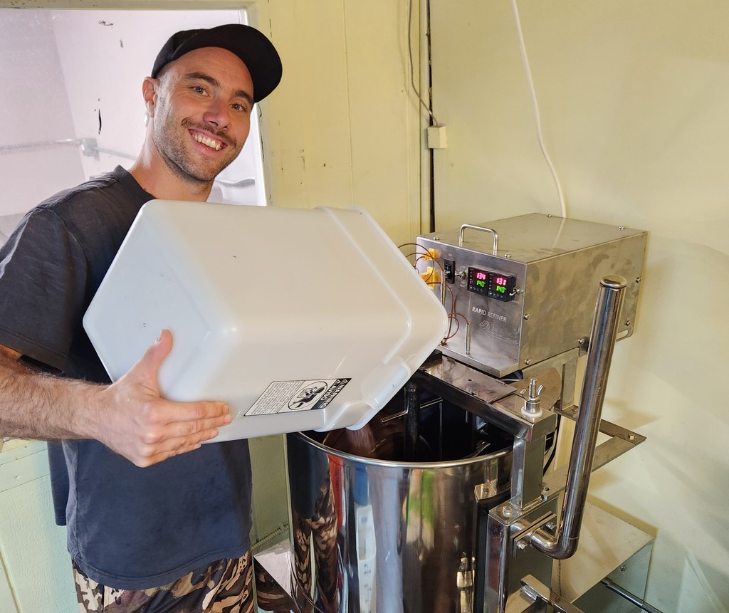 Chocolate maker Sam Phillips adds cacao nibs to the 100-pound melanger, where they will be ground into chocolate liquor (liquid chocolate).