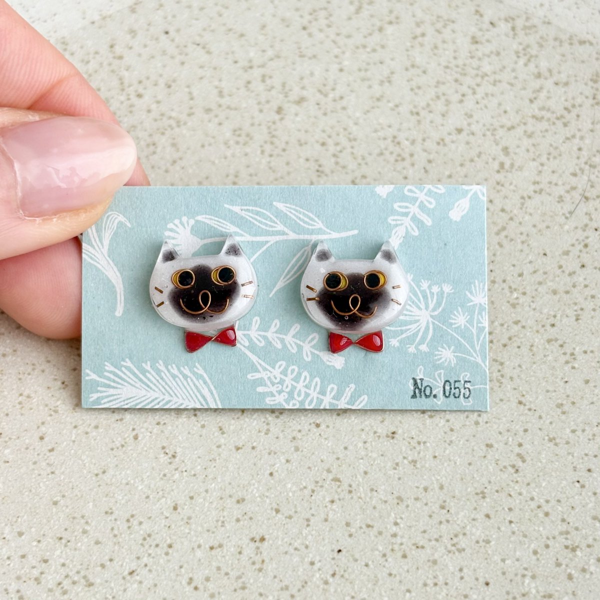 No0556's tweet photo. 【No.055】ニャンコ　猫　ピアス　ハチワレ　ブルーポイント　蝶ネクタイ
なかなかないブルーポイントちゃんのピアス😊😆

ニャンコの大きさは2×1.5センチのニャンコです。
１つずつ手作りで、針金を曲げて表情を作り、色付け、コーティングを重ねています。
1点ずつ顔が違いますので在庫は各1個のみ https://t.co/ynaAGWIR29