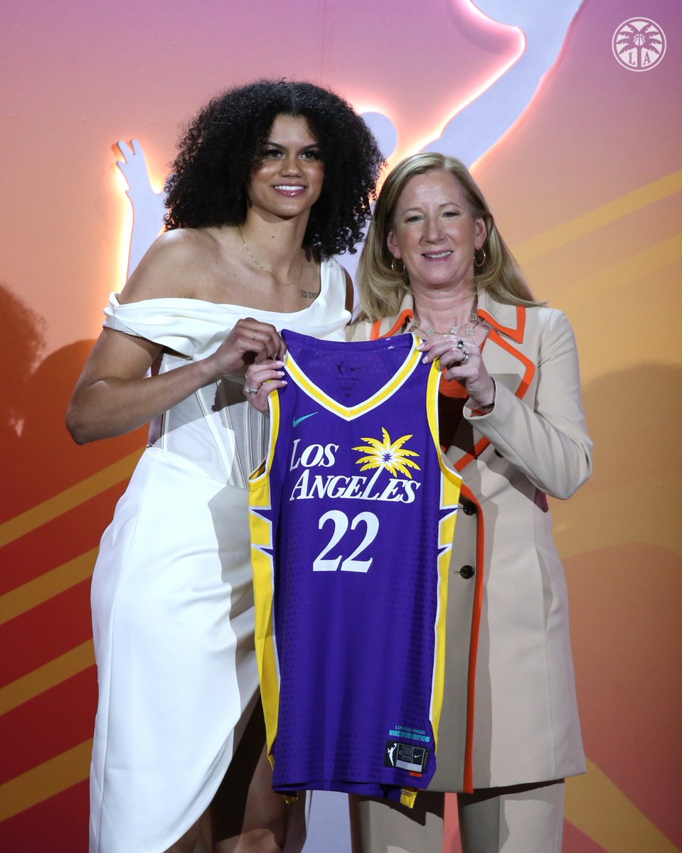 Rae Burrell holding up a Sparks jersey next to WNBA Commissioner Cathy Engelbert at the 2022 WNBA Draft.