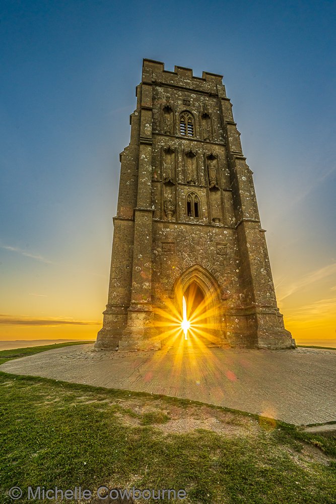 Glastomichelle's tweet photo. A bit of sparkle through the archway of St Michael's tower on Glastonbury Tor. Photograph taken this morning at sunrise. https://t.co/aIAchM2xHf