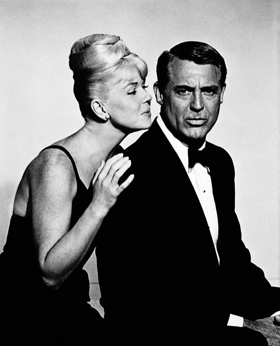 JuanmadelaPoza's tweet photo. ¿Cuál es la película más infravalorada de #DorisDay? Doris Day y #CaryGrant en una fotografía publicitaria de #SuaveComoElVisón (#ThatTouchOfMink, 1962), una comedia romántica fabulosa llena de enredos, malentendidos, confusiones y engaños dirigida por #DelbertMann. «Suave como el visón» narra la historia de Cathy Timberlake (Doris Day), una chica provinciana y chapada a la antigua, vive en Nueva York y su mayor deseo es enamorarse y crear un hogar feliz. Comparte piso con Connie (Autrey Meadows), otra chica en su misma situación. Un día, mientras Cathy acude a una entrevista de trabajo, un coche le salpica el vestido manchándoselo de barro. Es el Rolls Royce de Philip Shayne (Cary Grant), un atractivo millonario que enseguida muestra interés por ella. Philip la hechiza con su encanto y galantería, y le propone una serie de aventuras románticas de ensueño, pero sin pasar por la vicaría. Lo más inaudito para Doris Day es que lo hace de una forma exquisitamente elegante y respetuosa. La película tiene muchos momentos divertidísimos, como la confusión de las ancianas que recaudan fondos para ayudar a madres solteras, o los del psiquiatra escandalizado por las supuestas preferencias sexuales de un paciente. A partir de #ConLaMuerteEnLosTalones (#NorthByNorthwest, 1959), de #AlfredHitchcock, la estrella de Cary Grant fue apagándose poco a poco. Tras veinticinco años en lo más alto del panorama de #Hollywood caracterizando una y otra vez al galán de galanes por antonomasia, la huella inexorable de la edad dificultaba ya su identificación por parte del público con los atractivos, aventureros y descacharrantes personajes de sus comedias alocadas de juventud y de los elegantes y heroicos caballeros de su madurez, al mismo tiempo que afectaba a la verosimilitud de ciertas actitudes y comportamientos de sus caracteres en la pantalla. Esta autoconciencia de que su hueco indiscutible en el cine del sistema de estudios empezaba a faltarle llevó a Cary Grant a un espaciamiento cada vez mayor de sus apariciones en películas durante los años sesenta, hasta un retiro prematuro que le libró de tener que reinventarse en la vejez, como hicieron muchos otros intérpretes de su generación, exiliándose en proyectos menores de cine de catástrofes o en series de televisión de bajo perfil durante los años setenta. La lenta pero súbita caída del actor estadounidense de origen británico tuvo repuntes muy celebrados, como #PáginaEnBlanco (#TheGrassIsGreener, 1960) o #Charada (#Charade, 1963), ambas dirigidas por #StanleyDonen. Sin embargo, otras de sus películas dejaron bastante claro que su época en el cine había pasado. Aunque la presencia e interpretación de Cary Grant era lo mejor de estos filmes. Es el caso de «Suave como visón». Por el contrario, Doris Day se encontraba en su mejor momento profesional y estaba considerada el icono de la mujer virginal de clase media estadounidense. Así que era la actriz perfecta para interpretar el papel de Cathy Timberlake. La pareja cinematográfica formada por Doris Day y #RockHudson había tenido un éxito considerable con películas como #ConfidenciasAMedianoche, #PijamaParaDos y #NoMeMandesFlores. Rock Hudson confiaba en ser la pareja de Doris Day en esta película. Sin embargo, Delbert Mann se inclinó por Cary Grant.