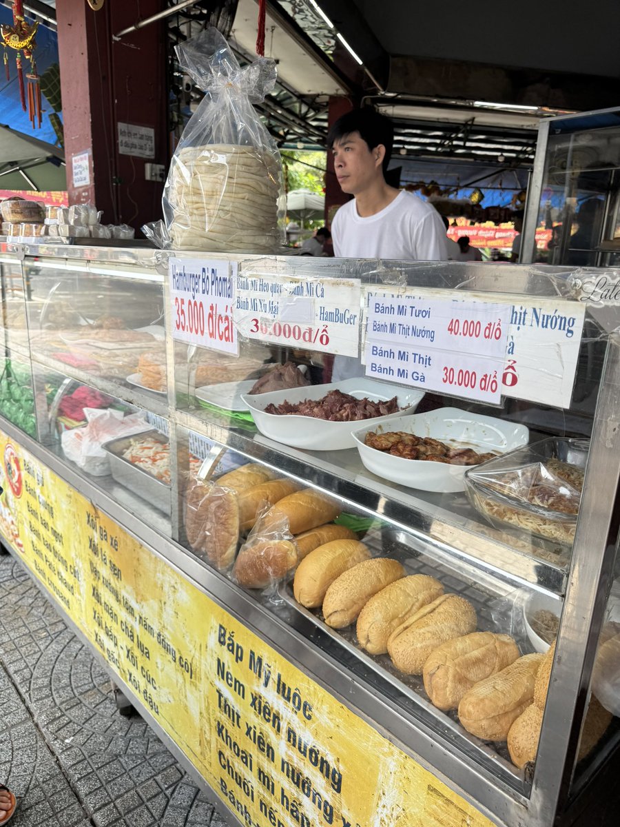 dashi_tsukkomi's tweet photo. バインミーニューランBánh Mì Như Lanは、地元では定番の老舗のベーカリー。中華まん、ハム、ソーセージの販売もある。バゲットに切れ目をいれて、パテ、野菜、ソーセージをはさんでくれる。「ノーチリ」と言わない限り、辛みもしっかり入る。 #bahnmi #hochiminh #食文化 #パン#pain #bread https://t.co/F9cVPZXKSr