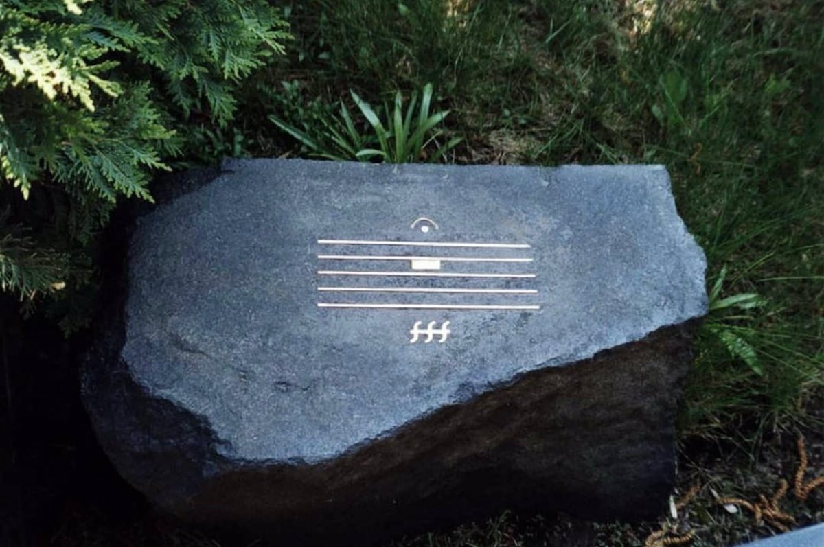The gravestone of Soviet-German composer Alfred Schnittke (1934-1998).

It's a musical staff with a semibreve (the center bar) indicating a rest or pause in the music. The fermata (the half circle + dot at the top) indicates to hold the note (in this case the rest) as long as