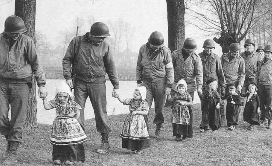 In 1944, amid the turmoil of WWII, a poignant moment was captured as American soldiers escorted Dutch children dressed in traditional national costumes. The scene offered a striking contrast between the innocence of youth and the gravity of war. These children, adorned in their