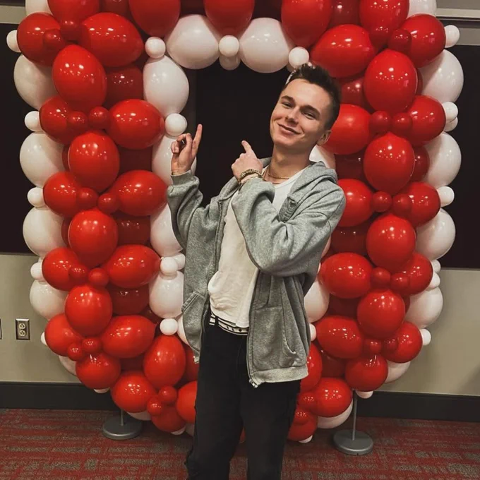 Incoming student in front of a balloon arch in the shape of an "O."