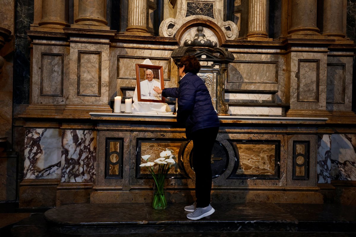 A woman touches a photograph of Pope Francis at the Sanctuary of Loyola, birthplace of Ignatius of Loyola, founder of the Jesuits, Catholic priest order to which late Pope Francis belonged, in Azpeitia, Spain, April 21, 2025. REUTERS/Vincent West