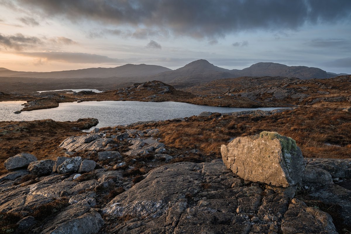 The rugged, ancient beauty of Lewisian gneiss, illuminated by the final rays of the day, stands in stark and stunning contrast to the white sands Harris is often celebrated for, its southern hills a distant, captivating backdrop.

#LewisianGneiss
#Harris
#OuterHebrides
#Scotland