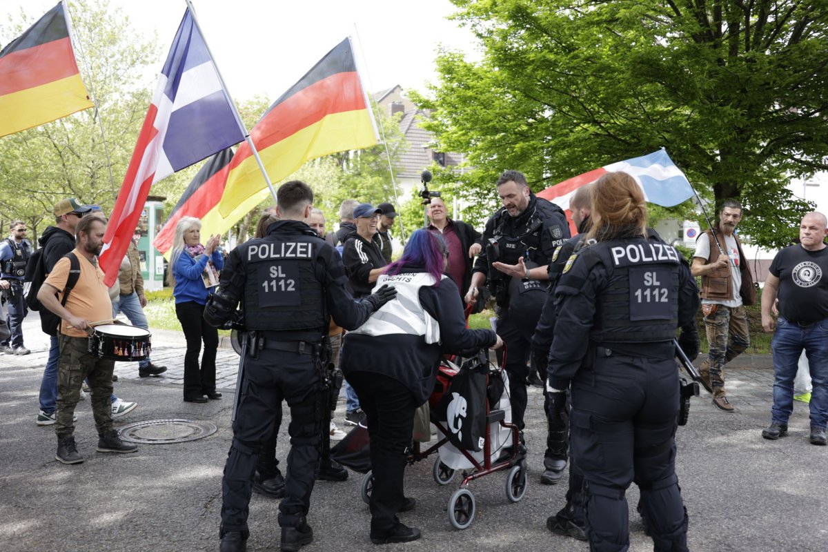 14:45 eine einzelne #OmasGegenRechts versucht den Marsch an einem Kreisel zu blockieren. Die Bereitschaftspolizei zerstört ihre Antifaflagge und drängt sie mit ihrem Rollator von der Strecke. #sls2604