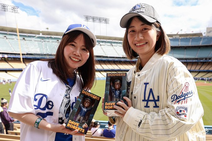 A photo of Dodger fans holding up their Dave Roberts bobbleheads.