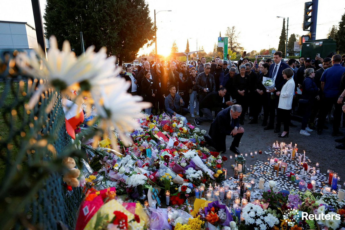Prime Minister Mark Carney kneels to pay tribute at a memorial as B.C. Premier David Eby stands with flowers near the site where a vehicle struck a crowd at a Filipino community Lapu Lapu Day event in Vancouver. Photography for <a href="/Reuters/">Reuters</a>