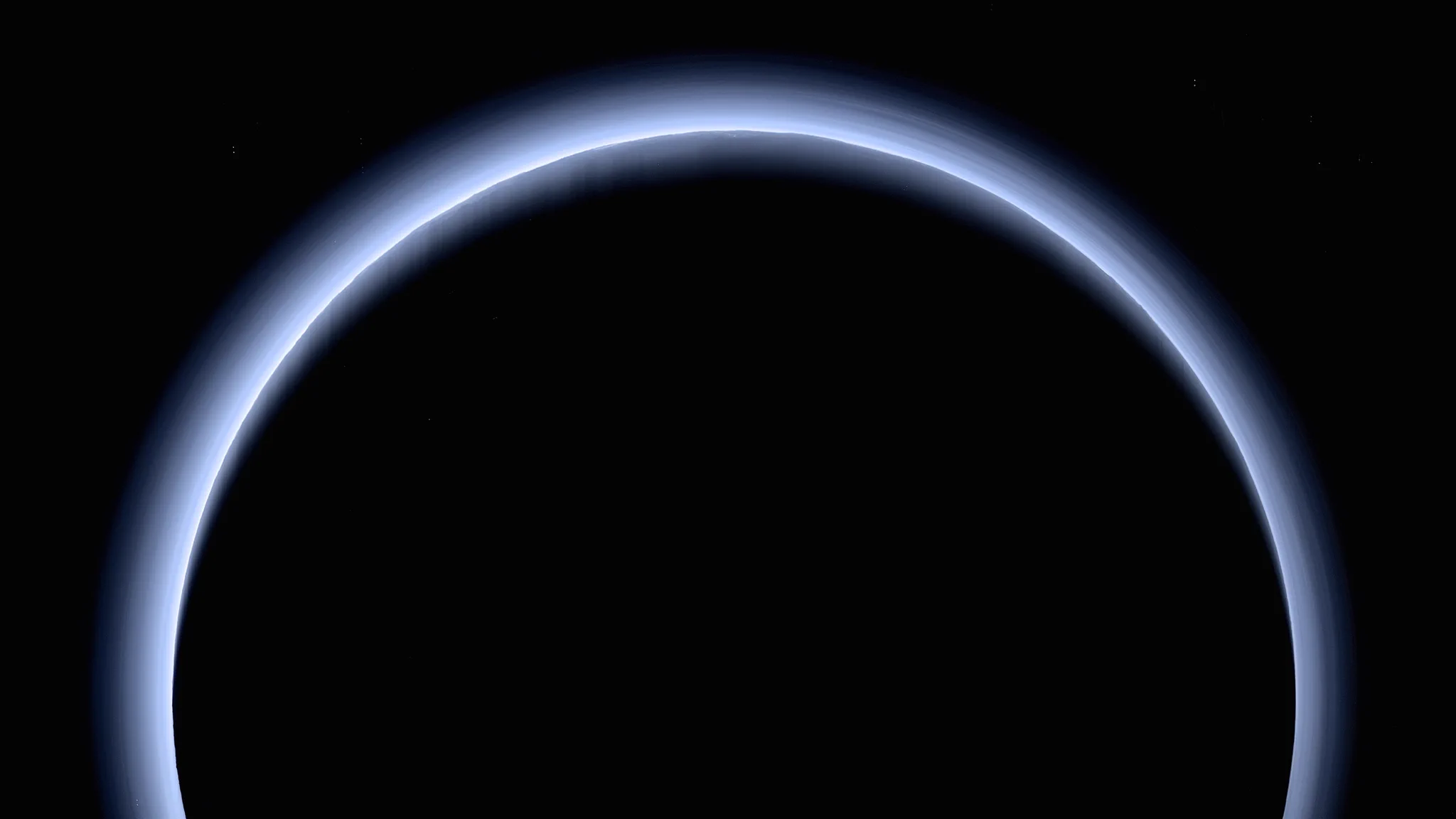 This is the highest-resolution color departure shot of Pluto’s crescent from NASA’s New Horizons, taken from 120,000 miles away. The image combines six LORRI black-and-white photos with color from Ralph/MVIC. It shows stunning blue atmospheric haze, caused by sunlight acting on methane to form hydrocarbons that scatter blue light. Layers stretch over 120 miles high. Surface mountains cast dramatic shadows through the haze, creating crepuscular rays. Image taken about 3.5 hours after closest approach on July 14, 2015. (Credit: NASA/Johns Hopkins APL/Southwest Research Institute)
